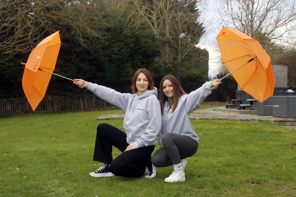 New members of the Satsuma team posing outside with orange umbrellas