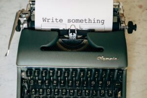 A typewriter with a piece of paper which says 'Write something'.