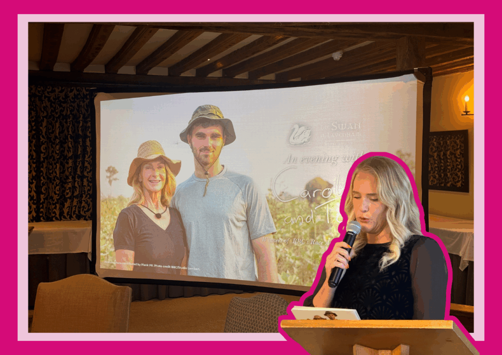 A projector screen showing an image of Caroline and Tom from BBC's Race Across the World, with Ellen Widdup standing at a podium speaking into a microphone.