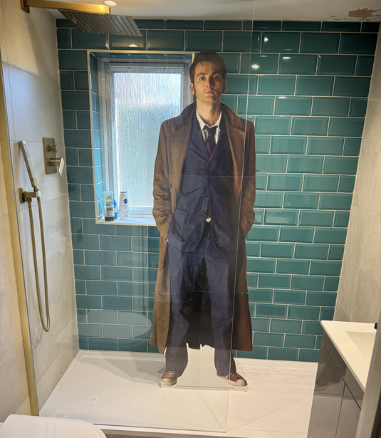 A life-size cardboard cut-out of David Tennant standing in a shower with green tiles behind him
