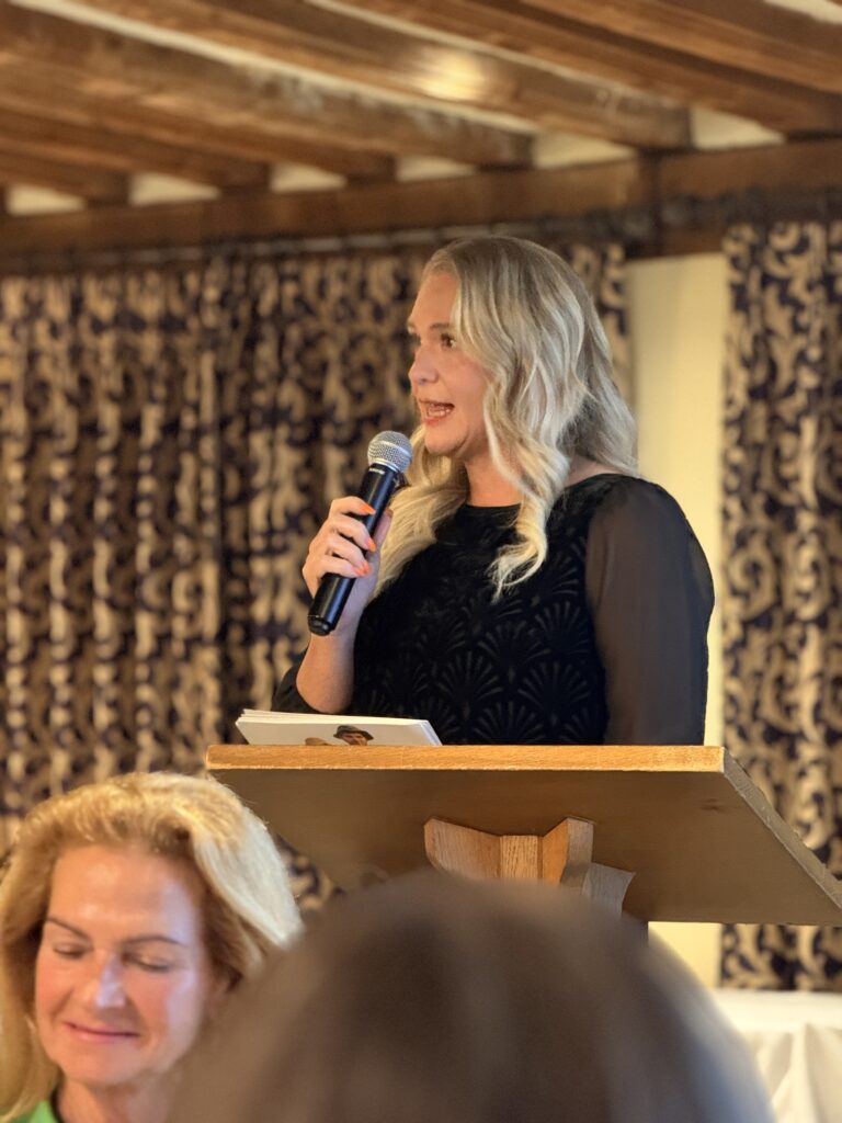 Ellen Widdup standing at a podium speaking into a microphone