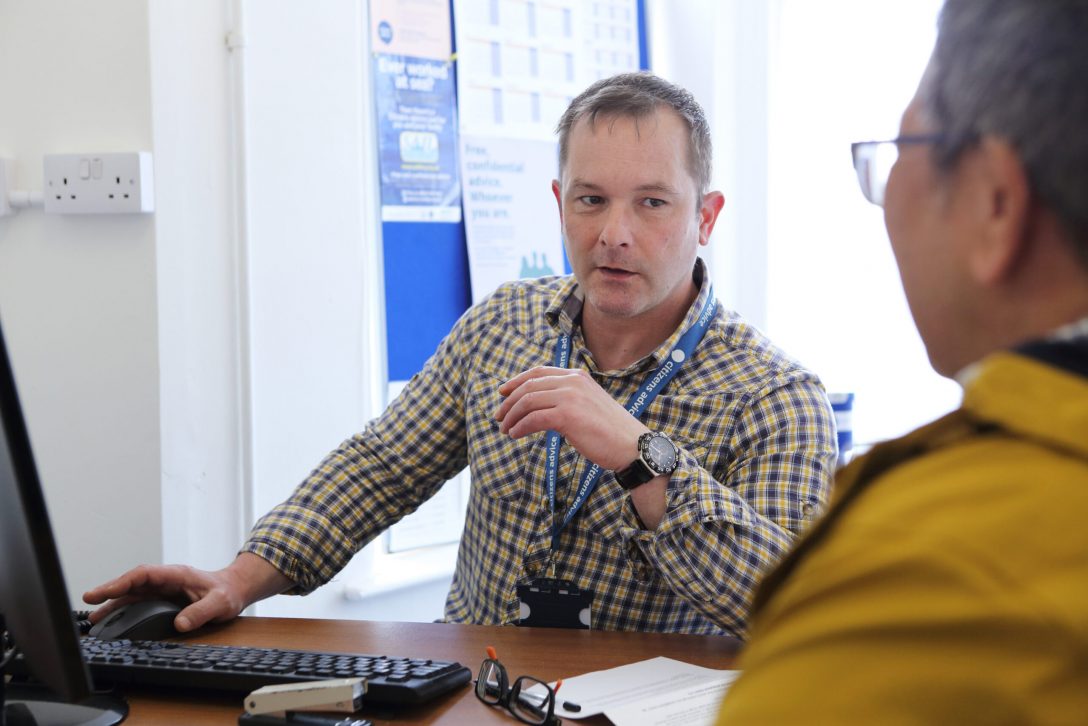 Man at a computer wearing a Citizens Advice lanyard